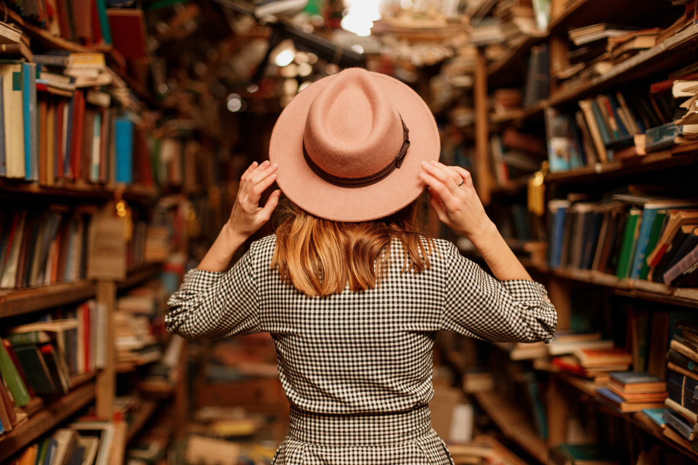 Woman Holding Her Hat in a Bookstore